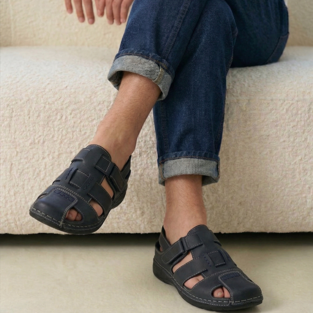 Man wearing dark navy comfortabşe Trefir sandals sitting on a beige couch